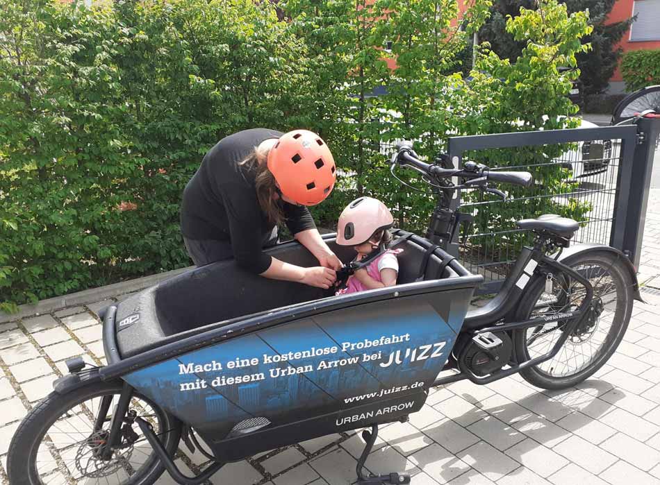 Mutter schnallt Kind im Lastenfahrrad an